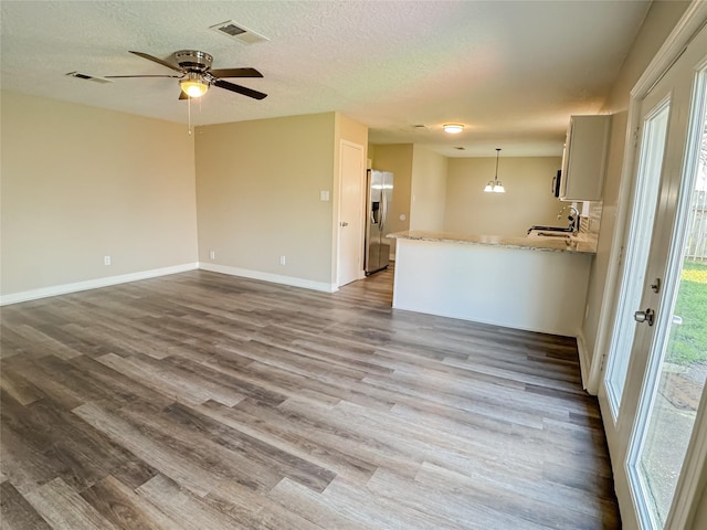 empty room featuring visible vents, a sink, a textured ceiling, and wood finished floors