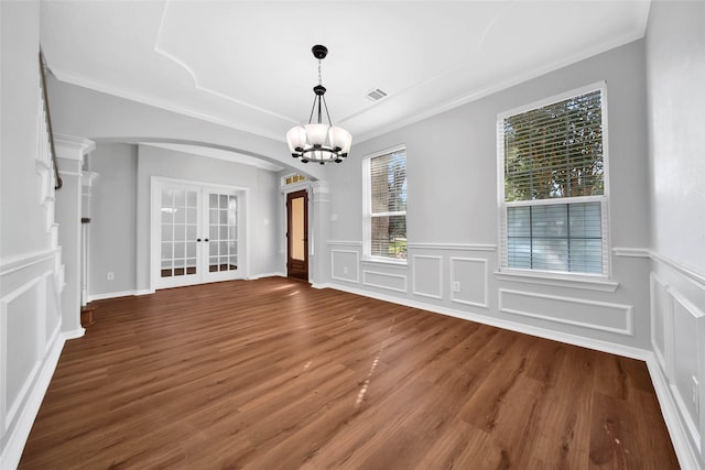 unfurnished dining area featuring arched walkways, french doors, visible vents, an inviting chandelier, and wood finished floors