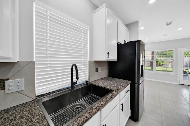 kitchen featuring light tile patterned floors, visible vents, decorative backsplash, white cabinetry, and a sink