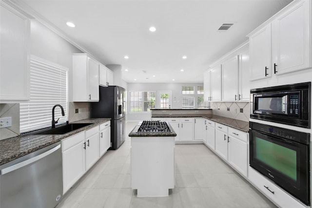 kitchen with visible vents, white cabinets, dark stone countertops, black appliances, and a sink