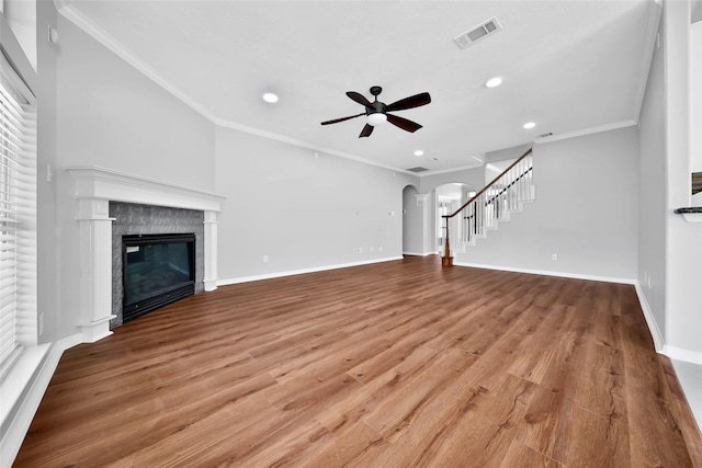 unfurnished living room with ornamental molding, arched walkways, visible vents, and a tile fireplace