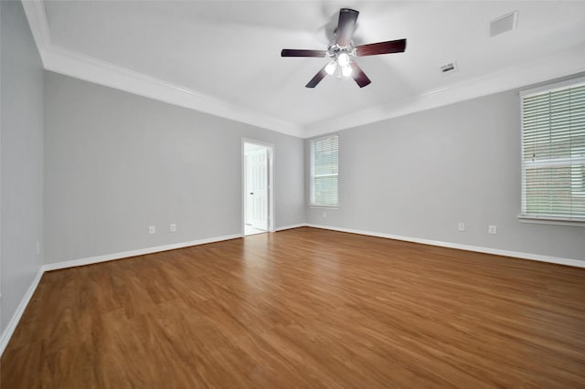 unfurnished room featuring visible vents, baseboards, crown molding, and wood finished floors