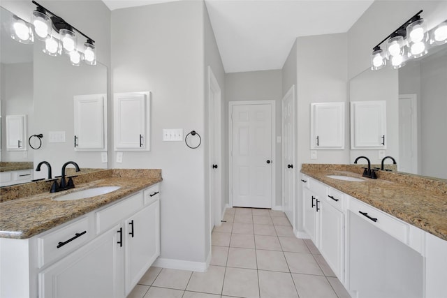 bathroom with tile patterned flooring, two vanities, a sink, and baseboards