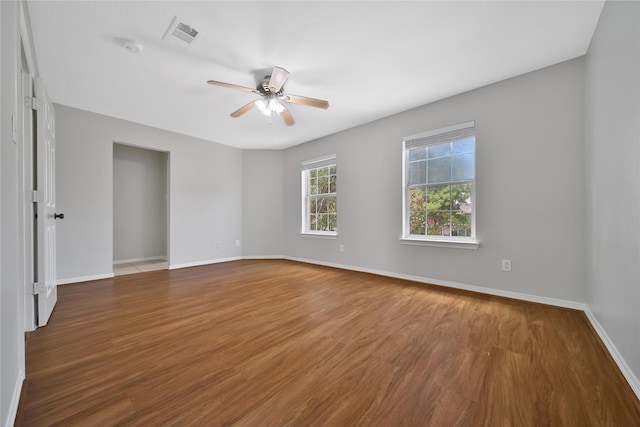 empty room featuring visible vents, wood finished floors, a ceiling fan, and baseboards