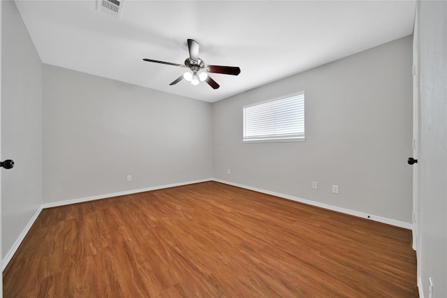 spare room featuring a ceiling fan, baseboards, visible vents, and wood finished floors