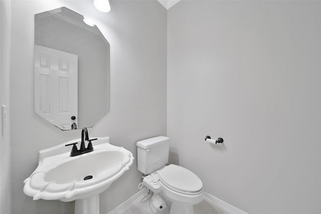 bathroom featuring toilet, baseboards, and a sink