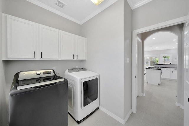 clothes washing area featuring ornamental molding, visible vents, cabinet space, and washer and clothes dryer