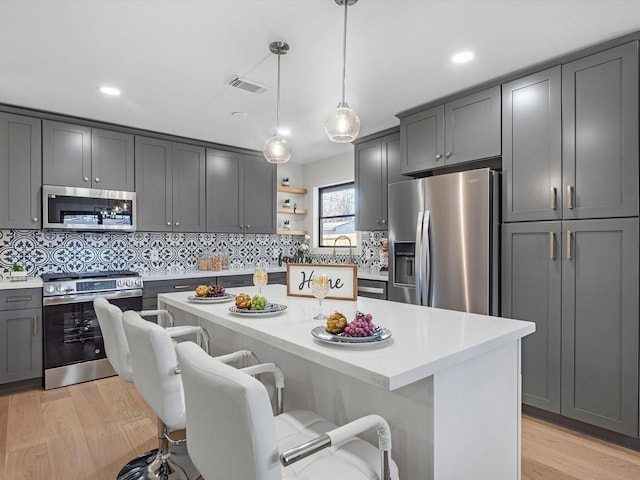 kitchen featuring stainless steel appliances, light wood-type flooring, visible vents, and a kitchen breakfast bar