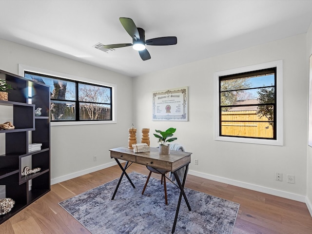 home office with ceiling fan, baseboards, a wealth of natural light, and wood finished floors