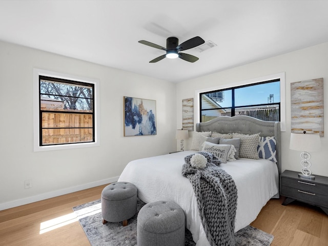 bedroom featuring ceiling fan, wood finished floors, visible vents, and baseboards
