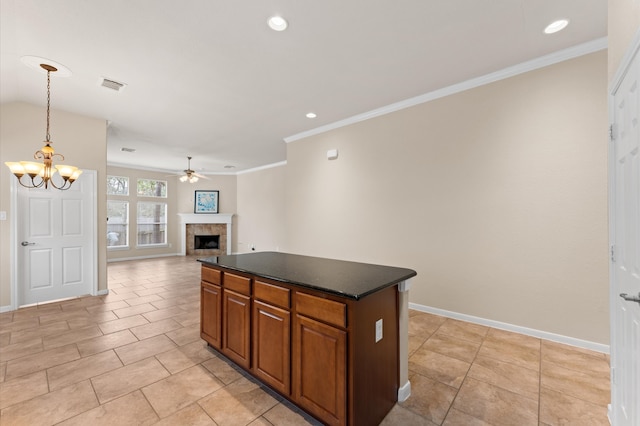 kitchen with a fireplace, visible vents, a center island, dark countertops, and crown molding