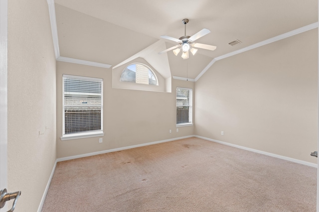 carpeted spare room with ceiling fan, visible vents, baseboards, vaulted ceiling, and ornamental molding