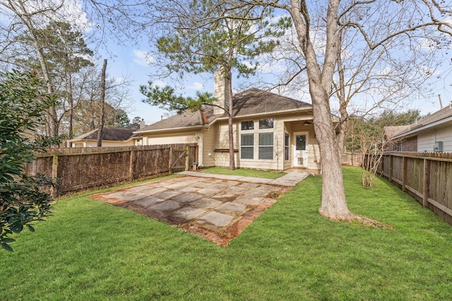 back of property with a fenced backyard, a chimney, a lawn, and a patio