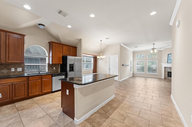 kitchen featuring decorative backsplash, dark countertops, lofted ceiling, appliances with stainless steel finishes, and a sink