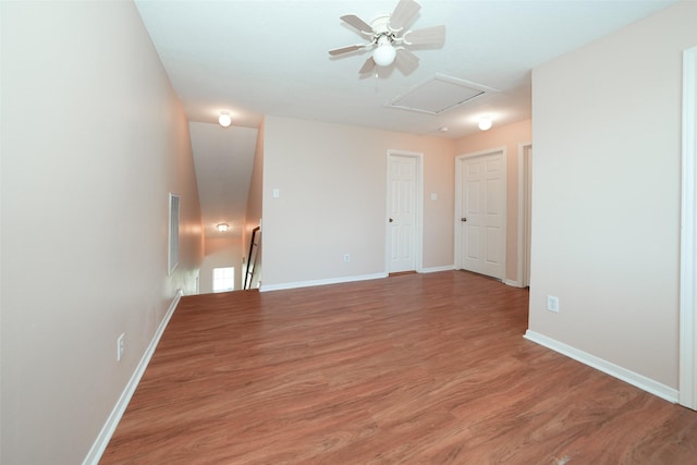 empty room with visible vents, light wood finished floors, attic access, and baseboards