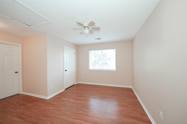 empty room featuring ceiling fan, light wood finished floors, visible vents, and baseboards