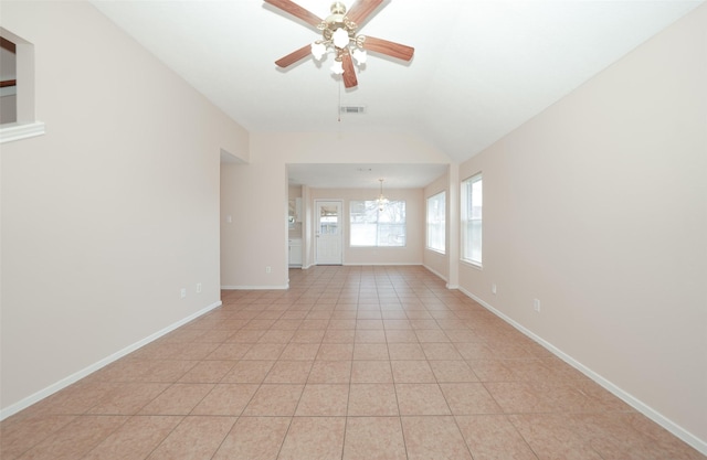 unfurnished room featuring ceiling fan with notable chandelier, light tile patterned flooring, lofted ceiling, and baseboards