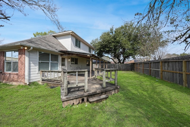 exterior space featuring a fenced backyard, a deck, a lawn, and brick siding