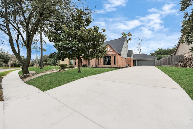 view of front of home with driveway, a garage, fence, a front lawn, and brick siding