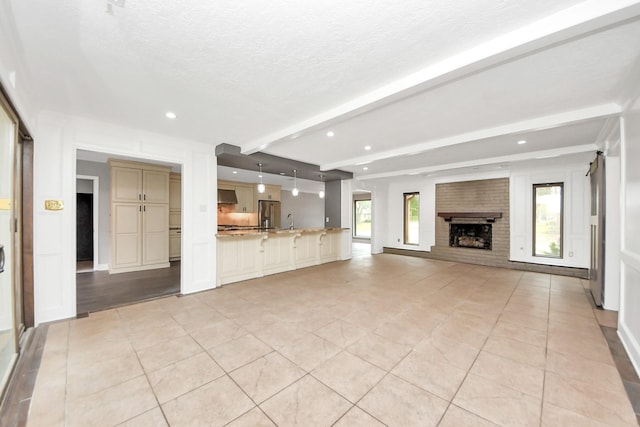 unfurnished living room with recessed lighting, beam ceiling, a textured ceiling, and light tile patterned floors