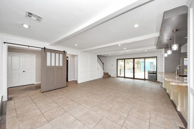 unfurnished living room featuring beam ceiling, recessed lighting, visible vents, stairway, and a barn door