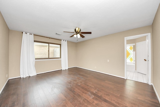 unfurnished room featuring ceiling fan, dark wood finished floors, visible vents, and baseboards