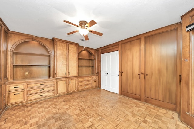 unfurnished bedroom with ceiling fan, wooden walls, visible vents, and a textured ceiling