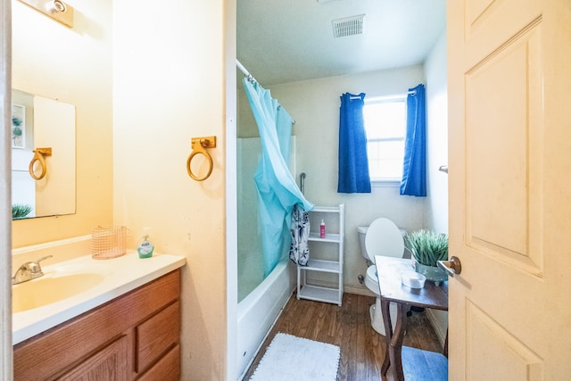 bathroom with visible vents, toilet, shower / bath combo with shower curtain, vanity, and wood finished floors