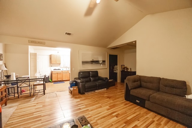 living area featuring lofted ceiling, visible vents, ceiling fan, and light wood-style flooring