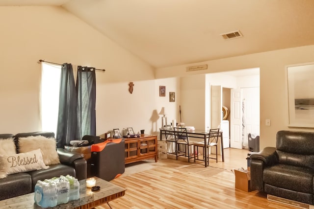 living area with visible vents, vaulted ceiling, and wood finished floors