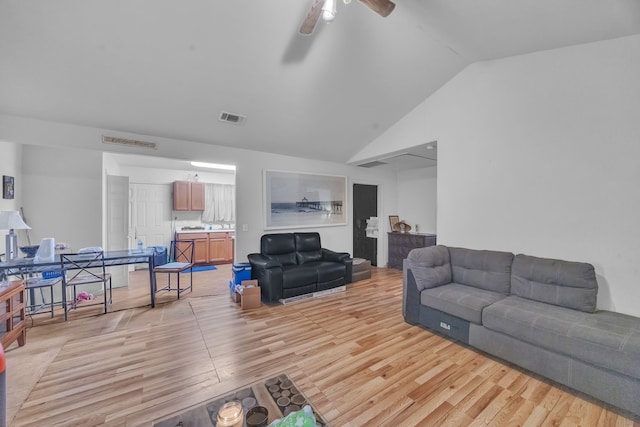 living room with vaulted ceiling, visible vents, and light wood-style floors