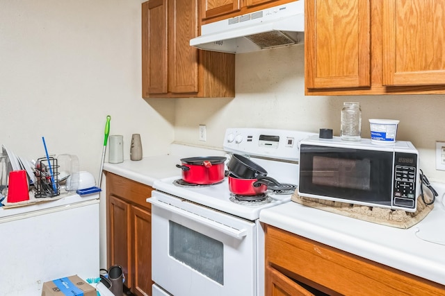 kitchen with brown cabinetry, white appliances, light countertops, and under cabinet range hood