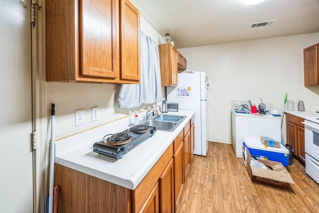 kitchen with light wood-style flooring, a sink, visible vents, light countertops, and brown cabinets