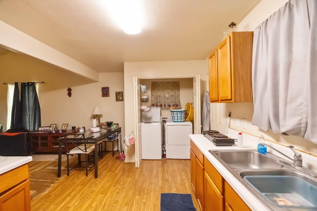 kitchen with separate washer and dryer, a sink, light countertops, light wood-type flooring, and brown cabinets