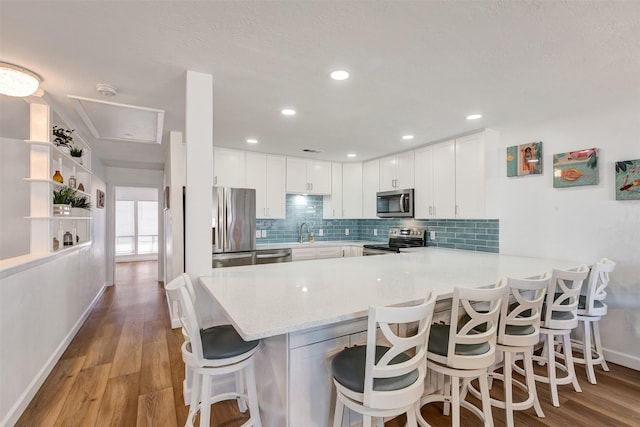 35 Regency Pt, Montgomery, TX 77356 - kitchen with appliances with stainless steel finishes, a peninsula, baseboards, white cabinets, and tasteful backsplash