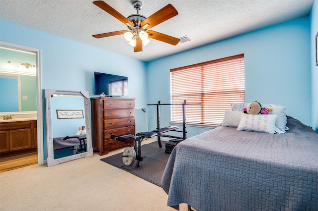 bedroom with visible vents, ensuite bathroom, light carpet, ceiling fan, and a textured ceiling