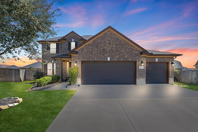 traditional-style home with brick siding, concrete driveway, an attached garage, a front yard, and fence