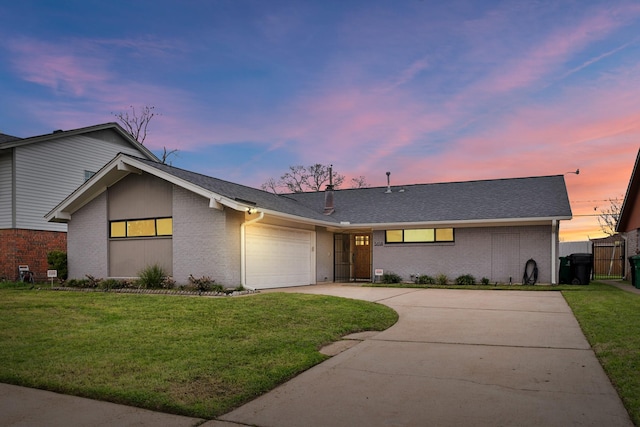 view of front of home with concrete driveway, roof with shingles, an attached garage, a front lawn, and brick siding