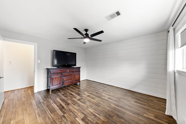 living room with a ceiling fan, visible vents, and dark wood-type flooring