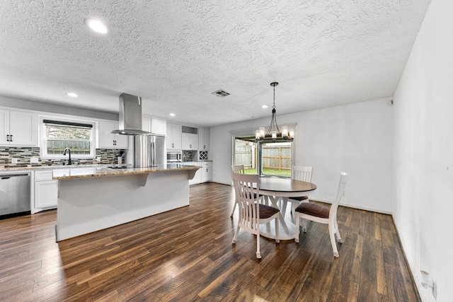 kitchen featuring a center island, pendant lighting, appliances with stainless steel finishes, white cabinets, and island range hood