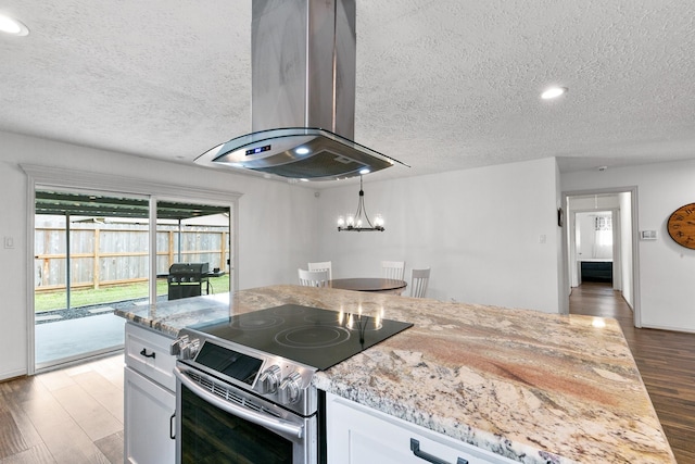 kitchen featuring stainless steel electric range oven, wood finished floors, light stone countertops, ventilation hood, and white cabinetry