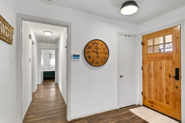 foyer with a textured ceiling, dark wood finished floors, and baseboards