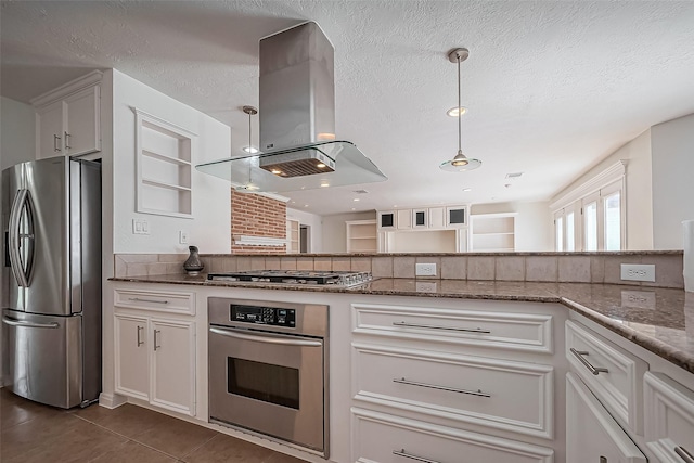 kitchen featuring island range hood, appliances with stainless steel finishes, hanging light fixtures, a textured ceiling, and dark tile patterned floors