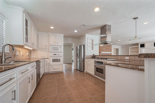 kitchen with stainless steel appliances, a sink, visible vents, white cabinets, and island exhaust hood