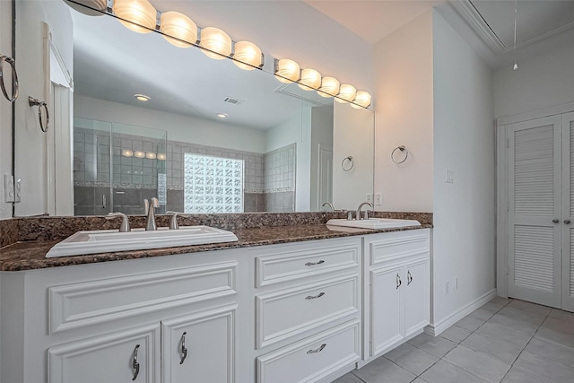 full bathroom with double vanity, tiled shower, a sink, and tile patterned floors