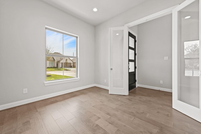 spare room featuring light wood-type flooring, recessed lighting, baseboards, and french doors