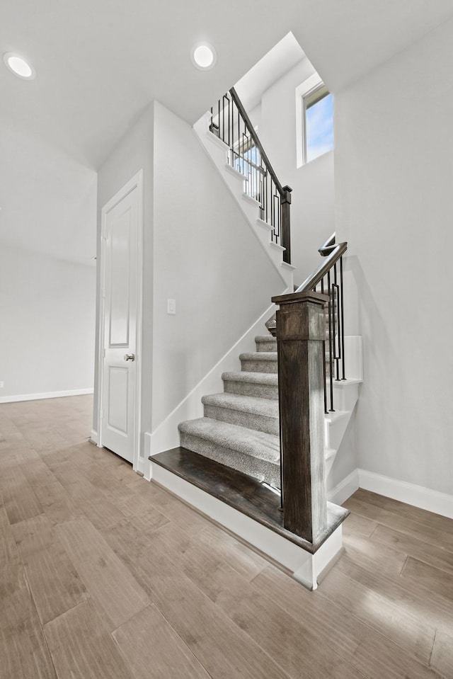 stairway featuring baseboards, wood finished floors, and recessed lighting