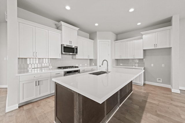 kitchen featuring stainless steel appliances, a sink, and light countertops