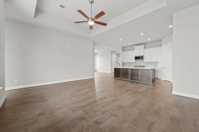 unfurnished living room with a raised ceiling and wood finished floors