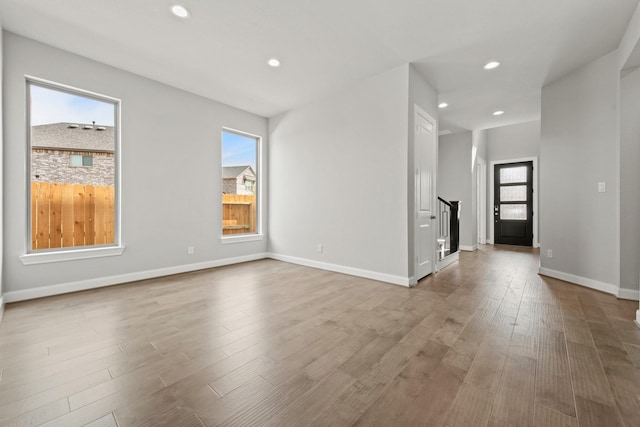 interior space with light wood-type flooring, baseboards, recessed lighting, and stairs